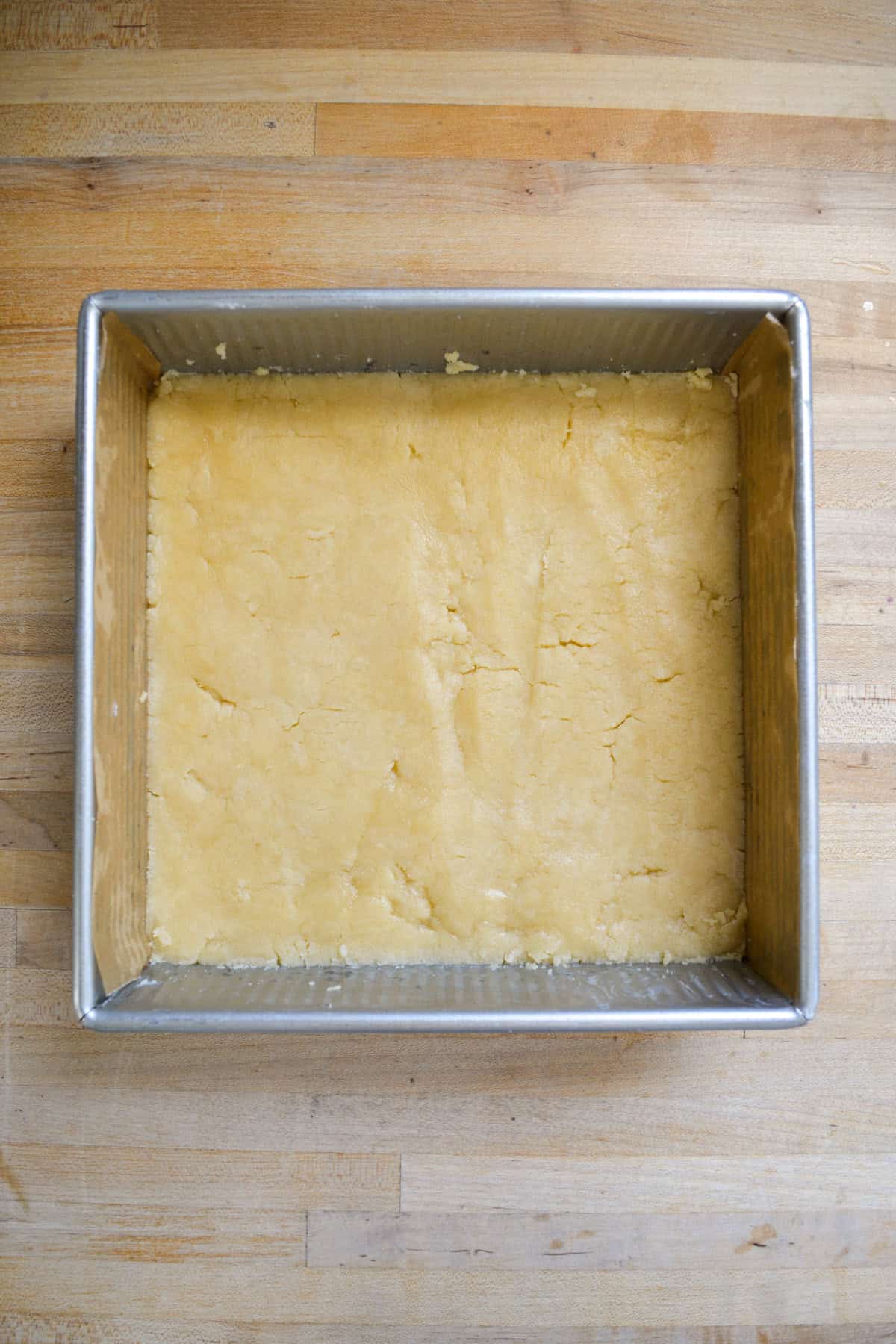Crust pressed into a square metal pan.