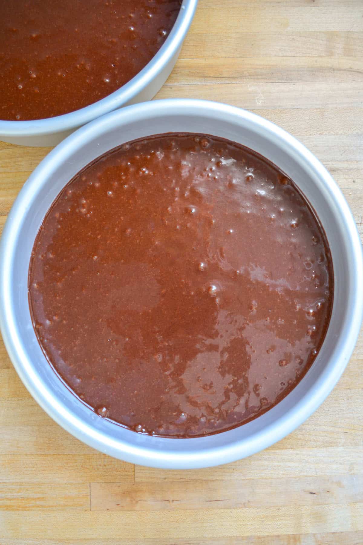Chocolate cake batter in a round cake pan.