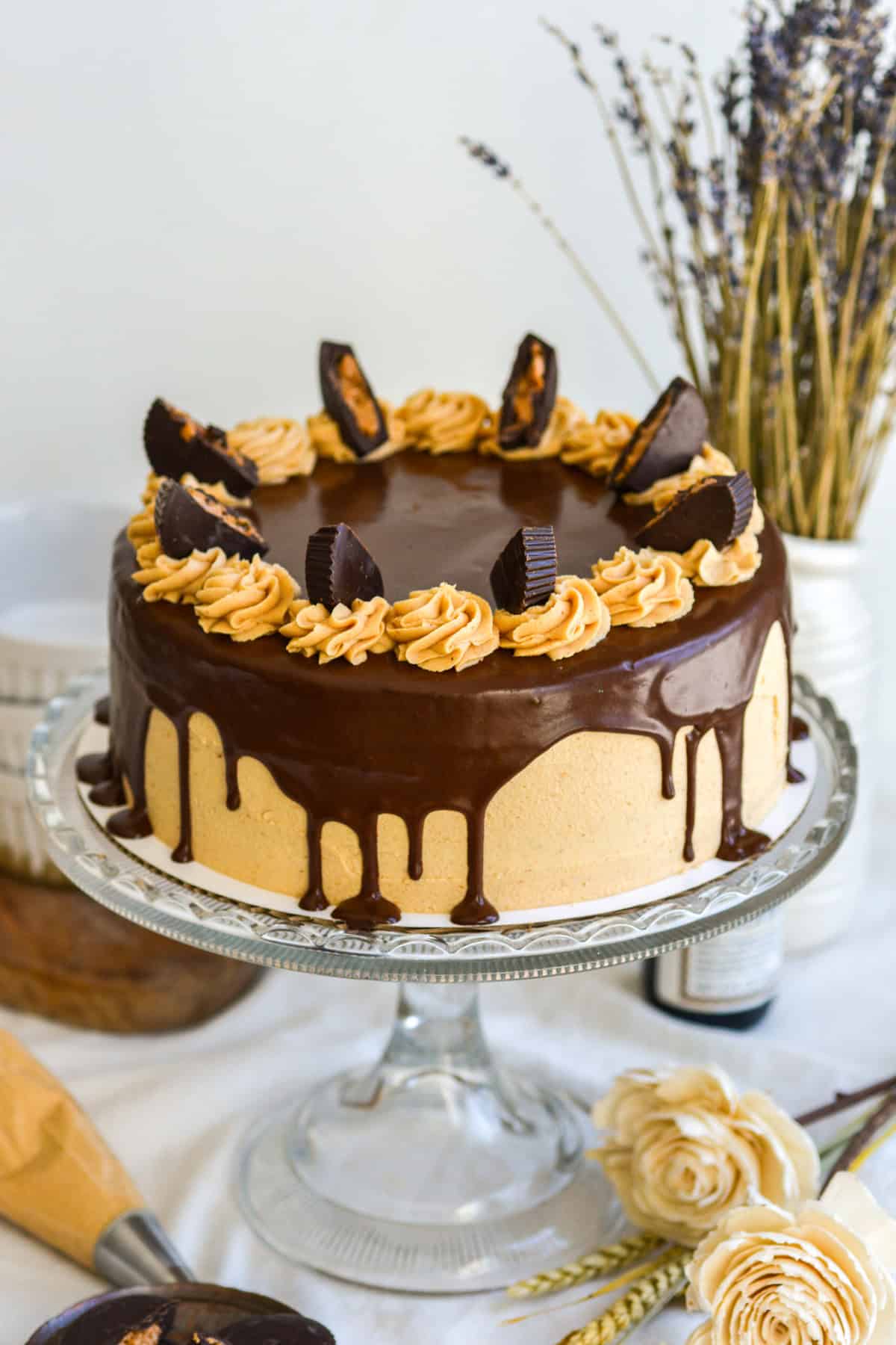 Chocolate Peanut Butter Cake topped with peanut butter cups on a glass cake stand.