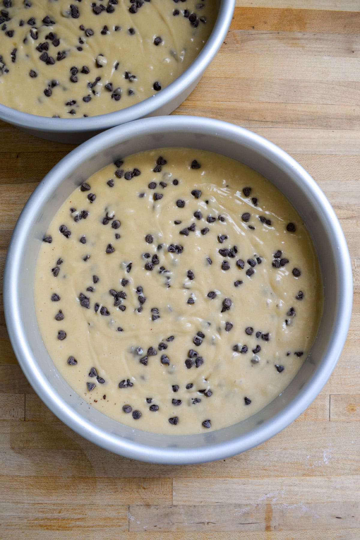 Cake batter topped with chocolate chips in a round cake pan.