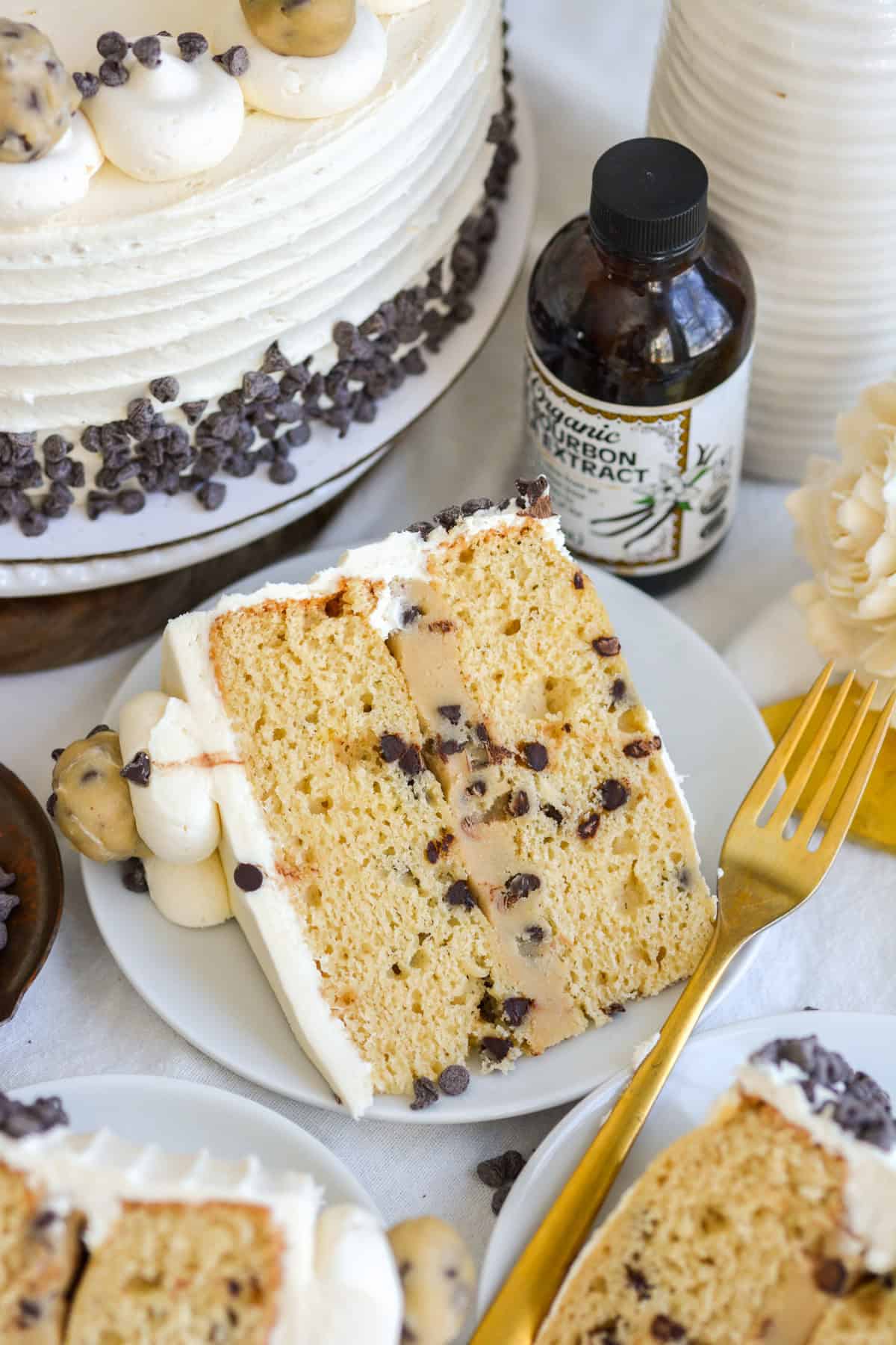 A slice of Vegan Cookie Dough Cake on a small plate with a gold fork.