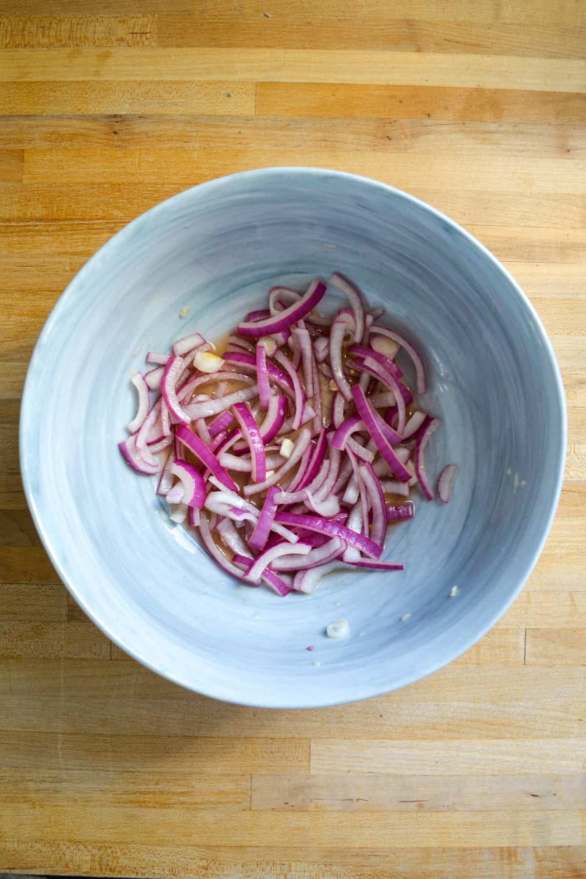Sliced onion marinating in vinegar in a large bowl.