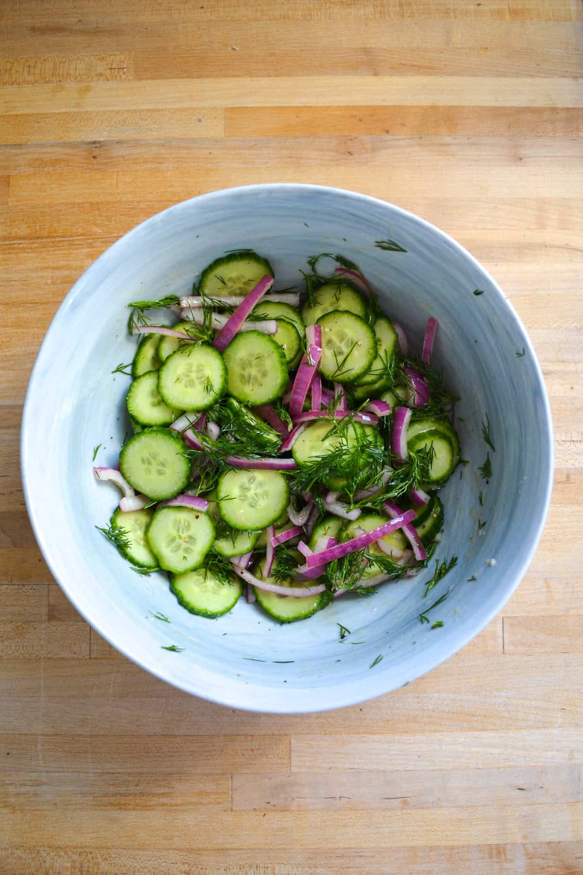 Sliced cucumber and dill added into the bowl.
