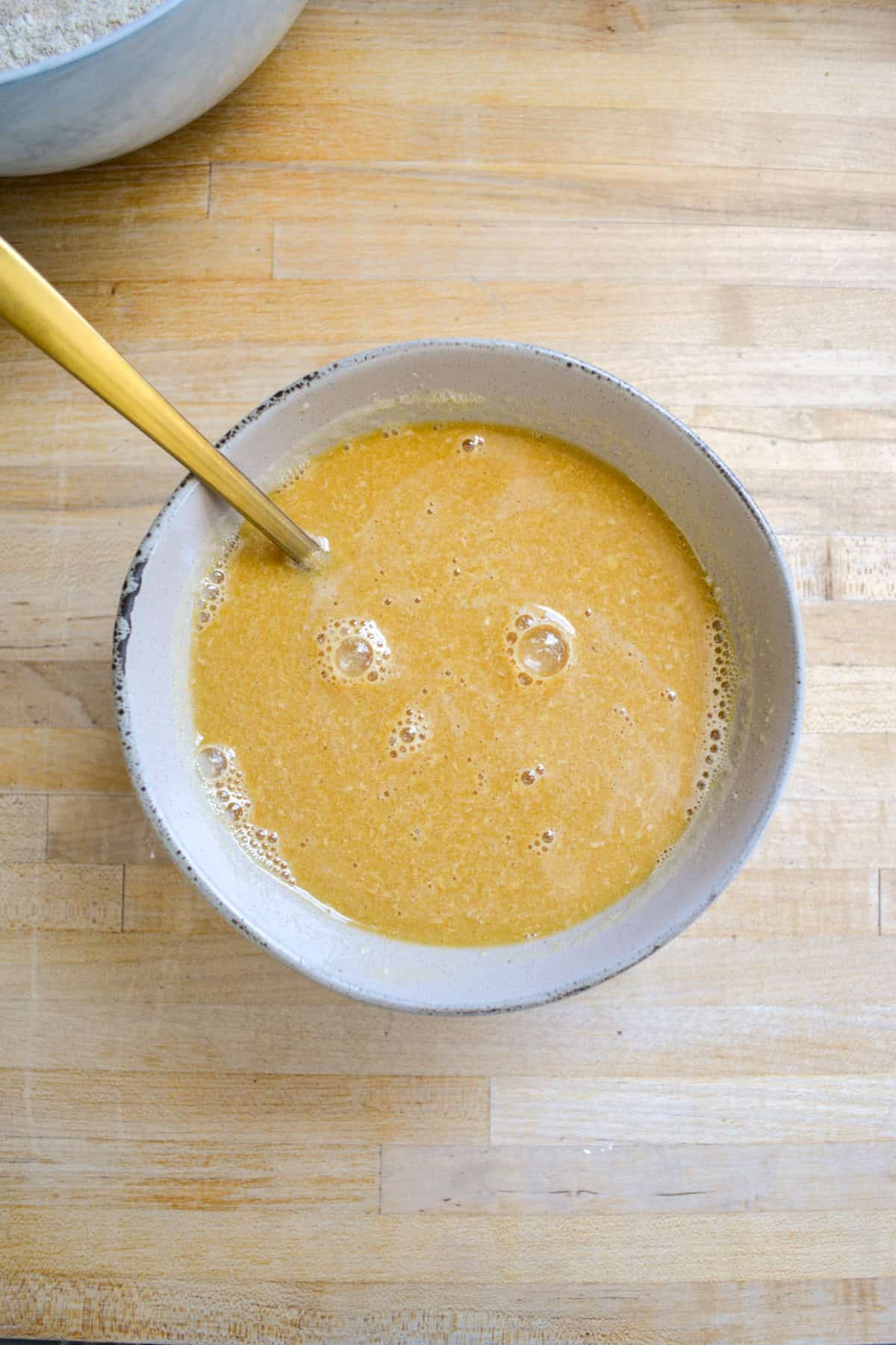 Wet ingredients in a medium bowl on a wooden surface.