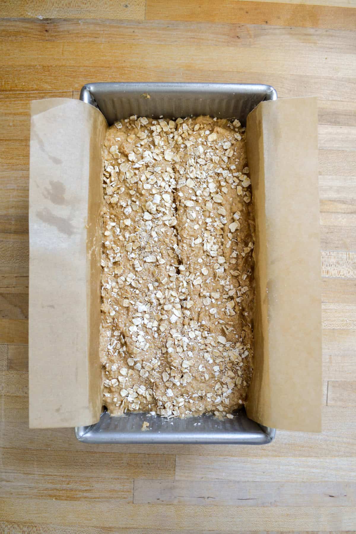 Bread batter in a loaf pan topped with rolled oats.