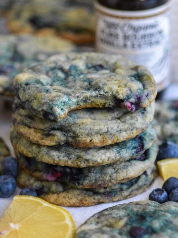 A stack of Vegan Blueberry Lemon Cookies with a bite taken out of the top cookie.