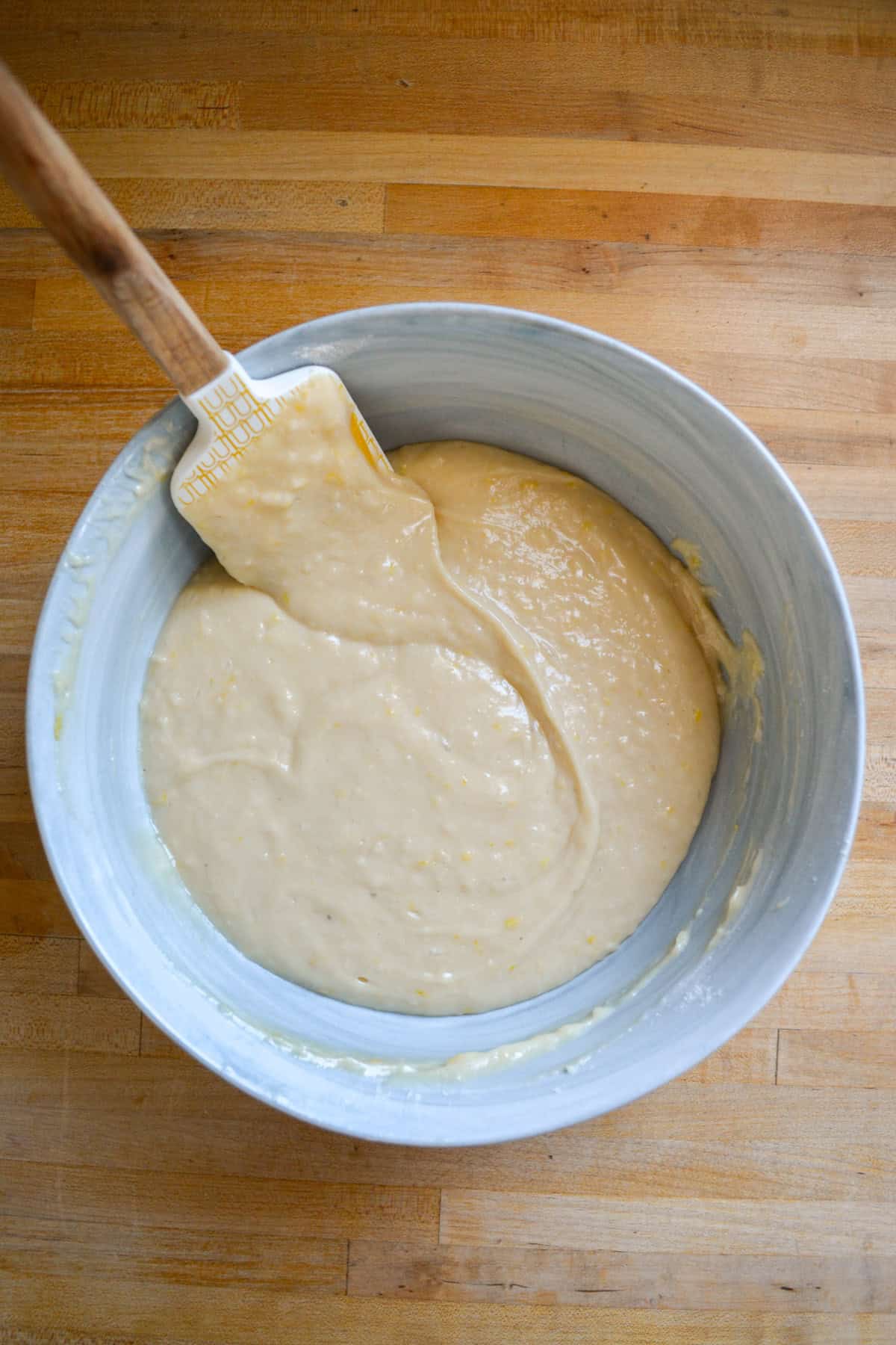 Cake batter in a large mixing bowl on a wooden surface.
