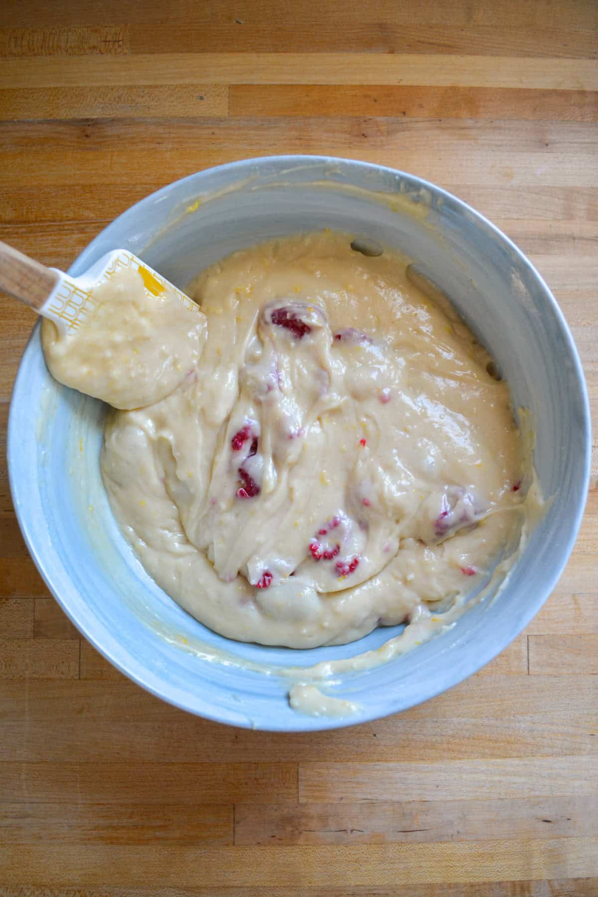 Raspberries folded into the cake batter in a large mixing bowl.