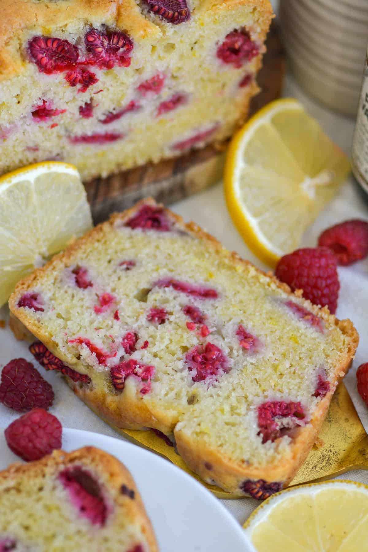 A slice of Vegan Raspberry Lemon Loaf Cake on a linen cloth.