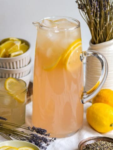 Lavender Lemonade in a pitcher with lemon slices and ice.