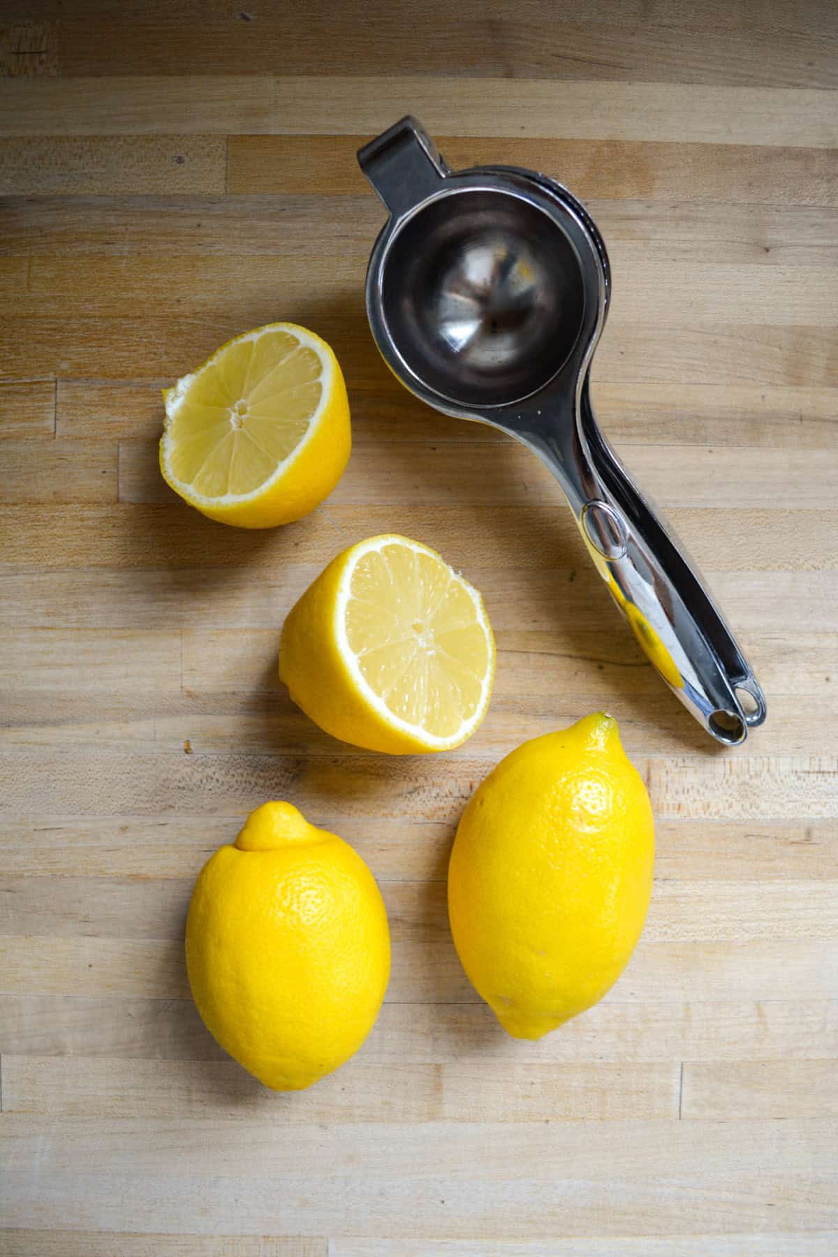 Lemons on a wooden surface with a citrus juicer.