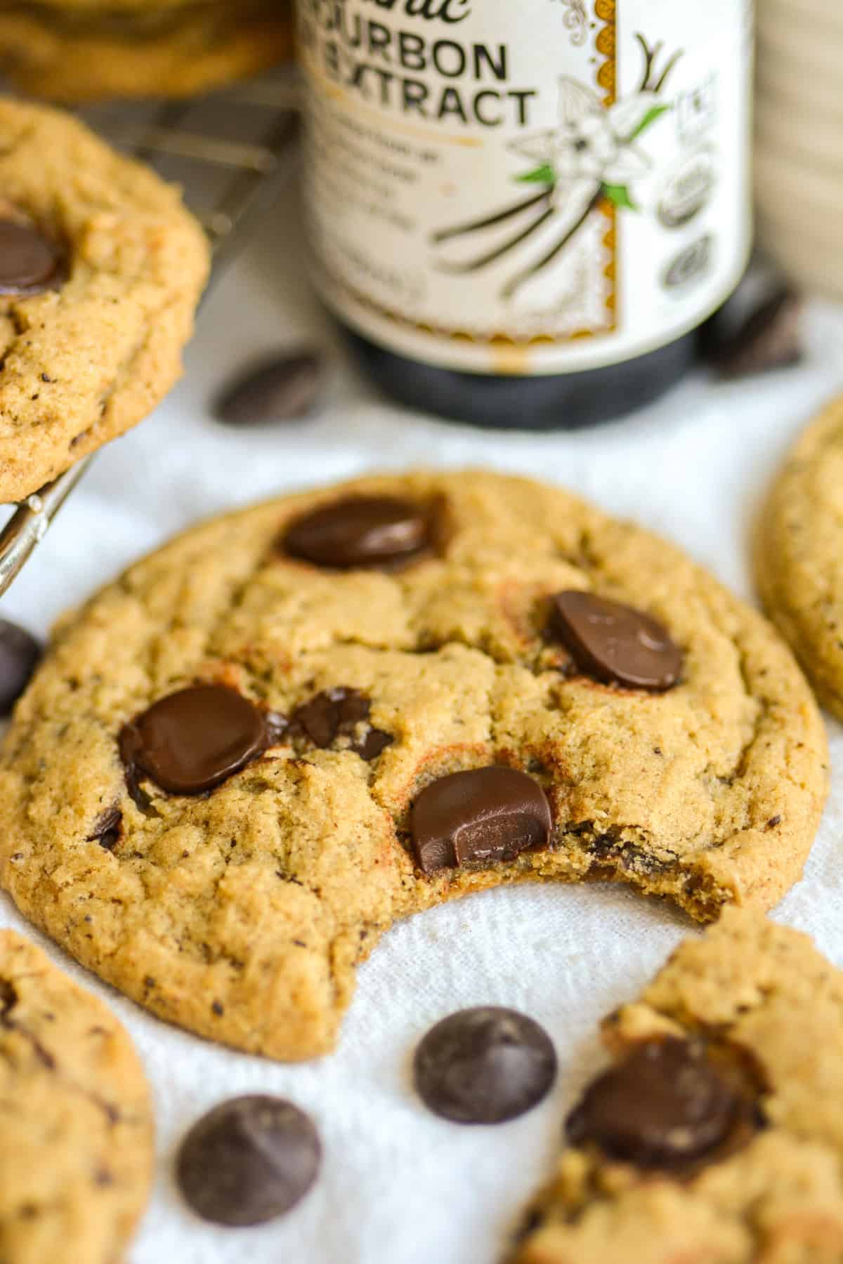 A Vegan Coffee Chocolate Chip Cookie with a bite taken out of it on a linen surface.