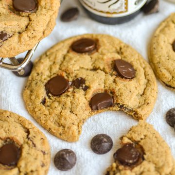 A Vegan Coffee Chocolate Chip Cookie with a bite taken out of it on a linen surface.