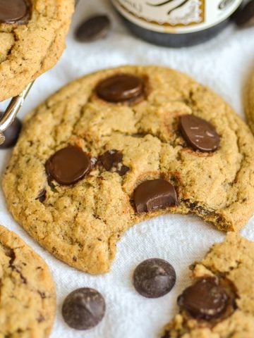 A Vegan Coffee Chocolate Chip Cookie with a bite taken out of it on a linen surface.
