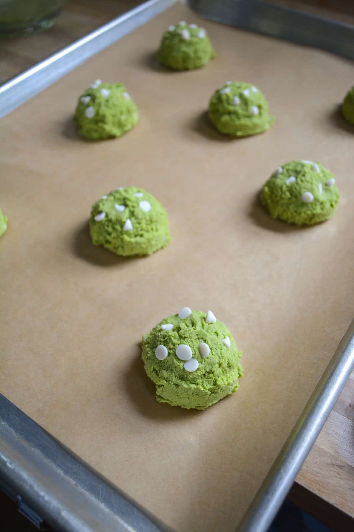 Scooped cookies on a parchment-lined baking sheet.