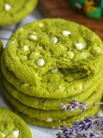 A stack of Vegan Matcha White Chocolate Cookies with a bite taken out of the top cookie.