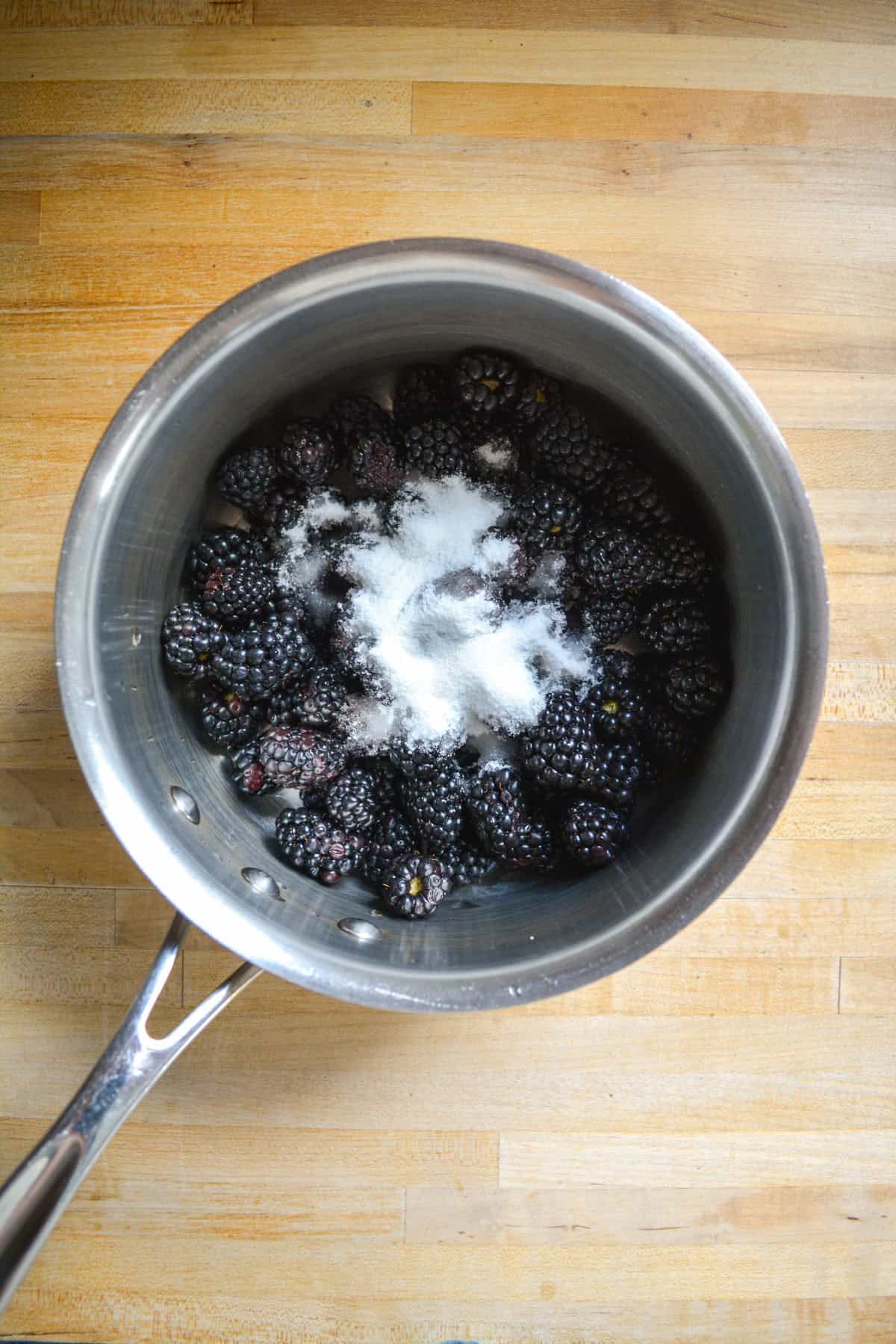 Blackberries and sugar in a saucepan.