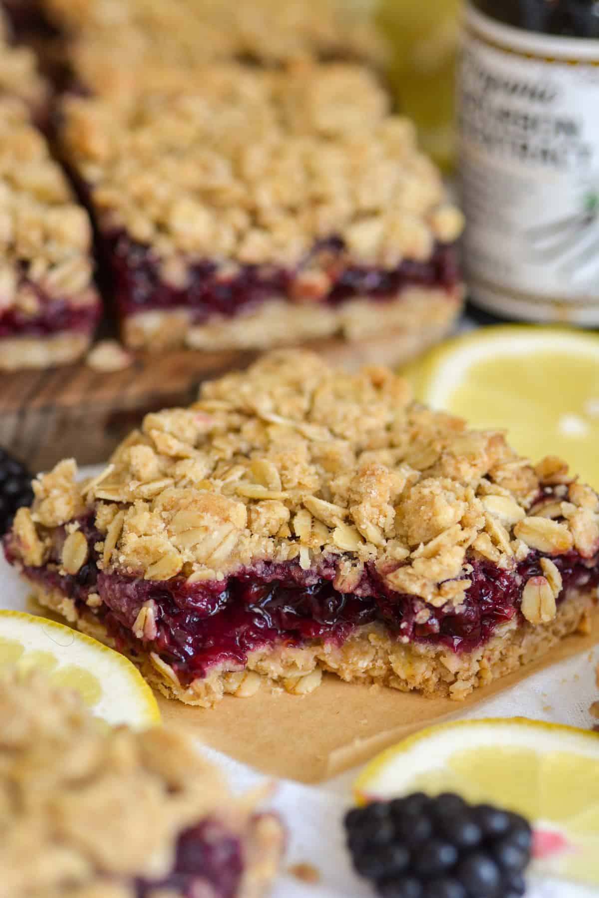 A blackberry oat bar on a parchment square with a bite taken out of it.