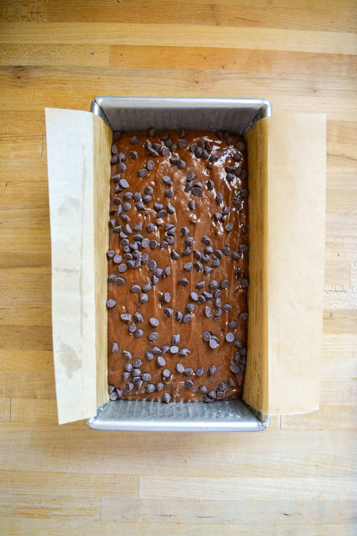 Batter in a loaf pan topped with chocolate chips.