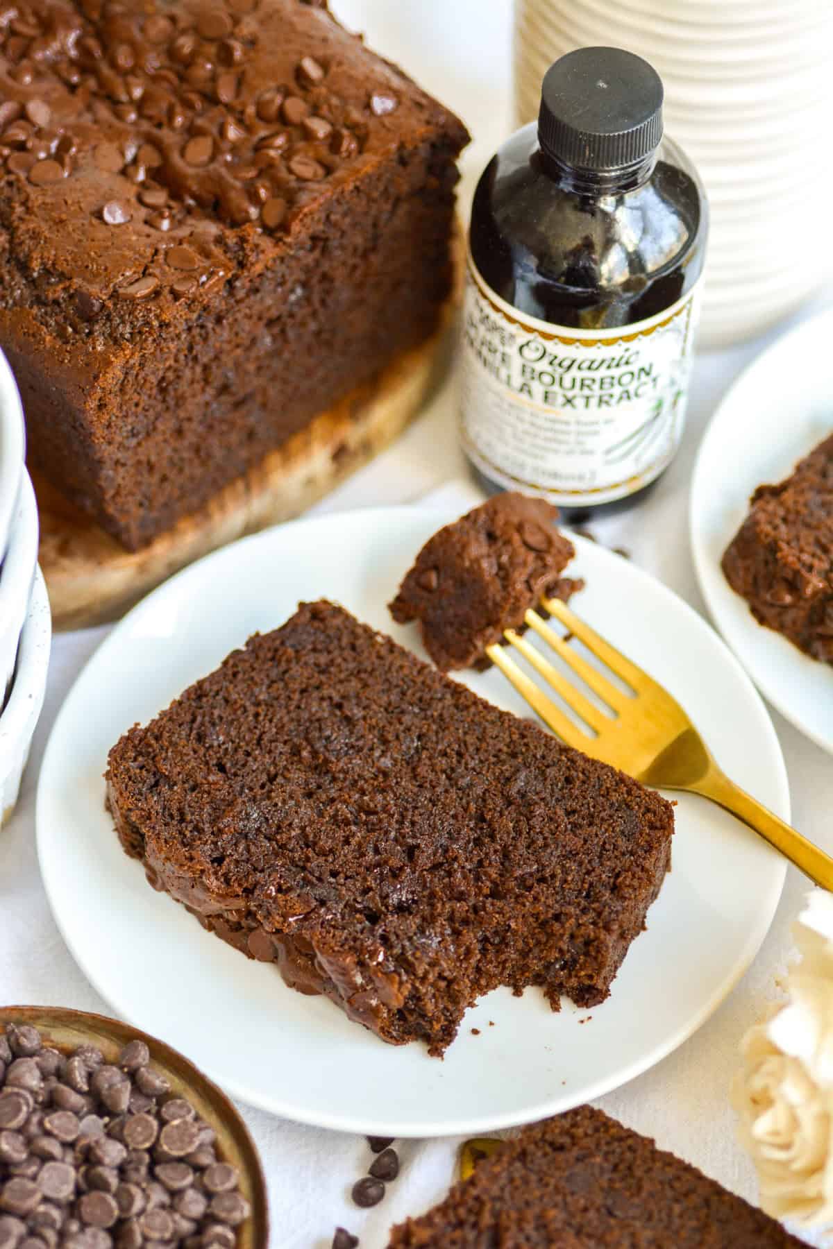 A slice of Chocolate Chocolate Chip Loaf Cake on a small plate with a gold fork.