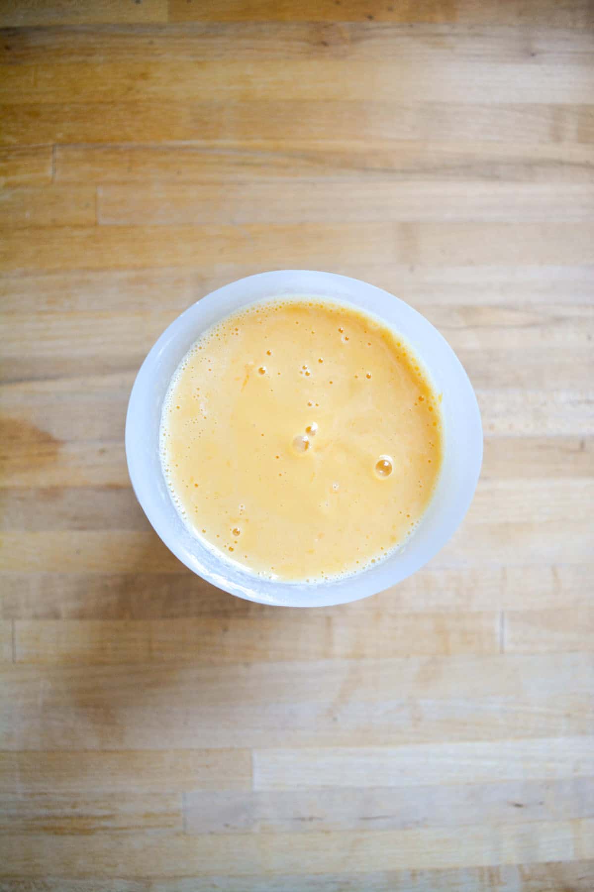 Milk and mango blended together in a measuring cup.