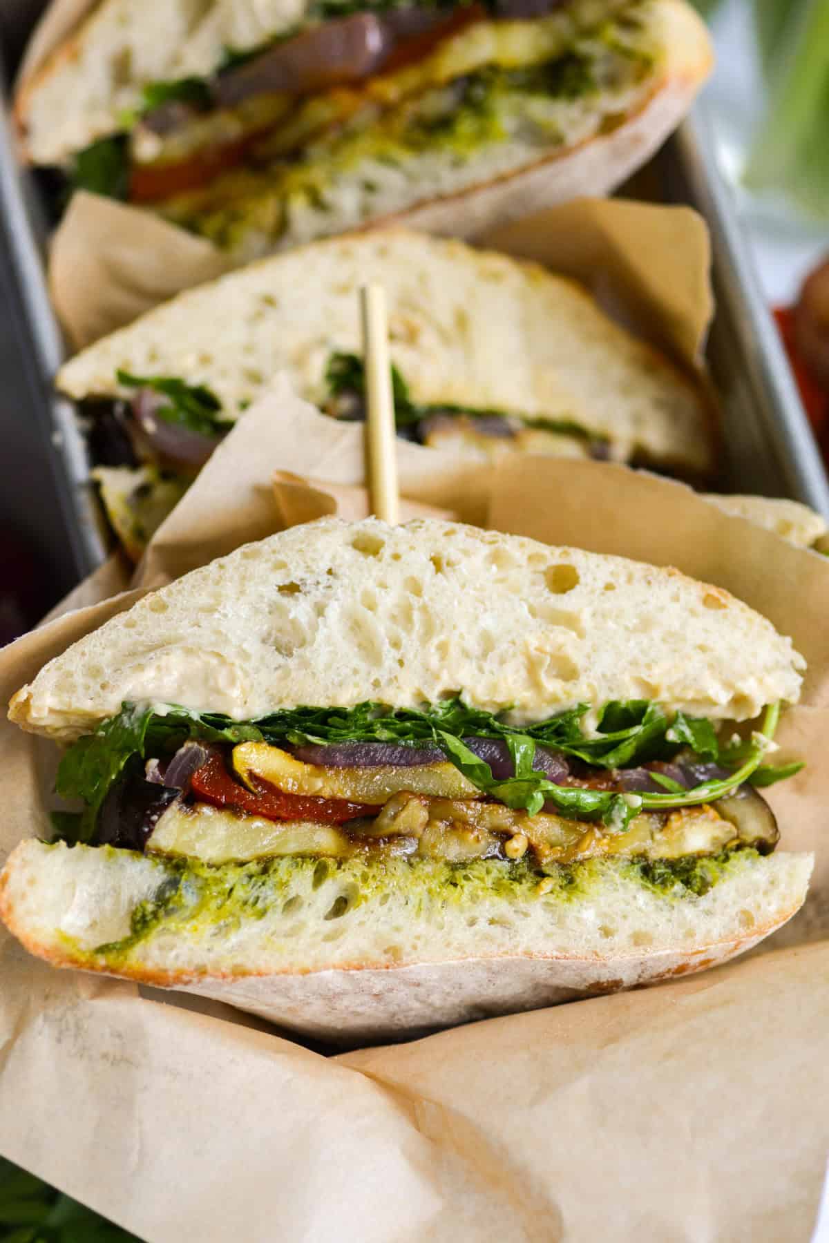 Roasted Vegetable Sandwich cut in half and wrapped in parchment paper.