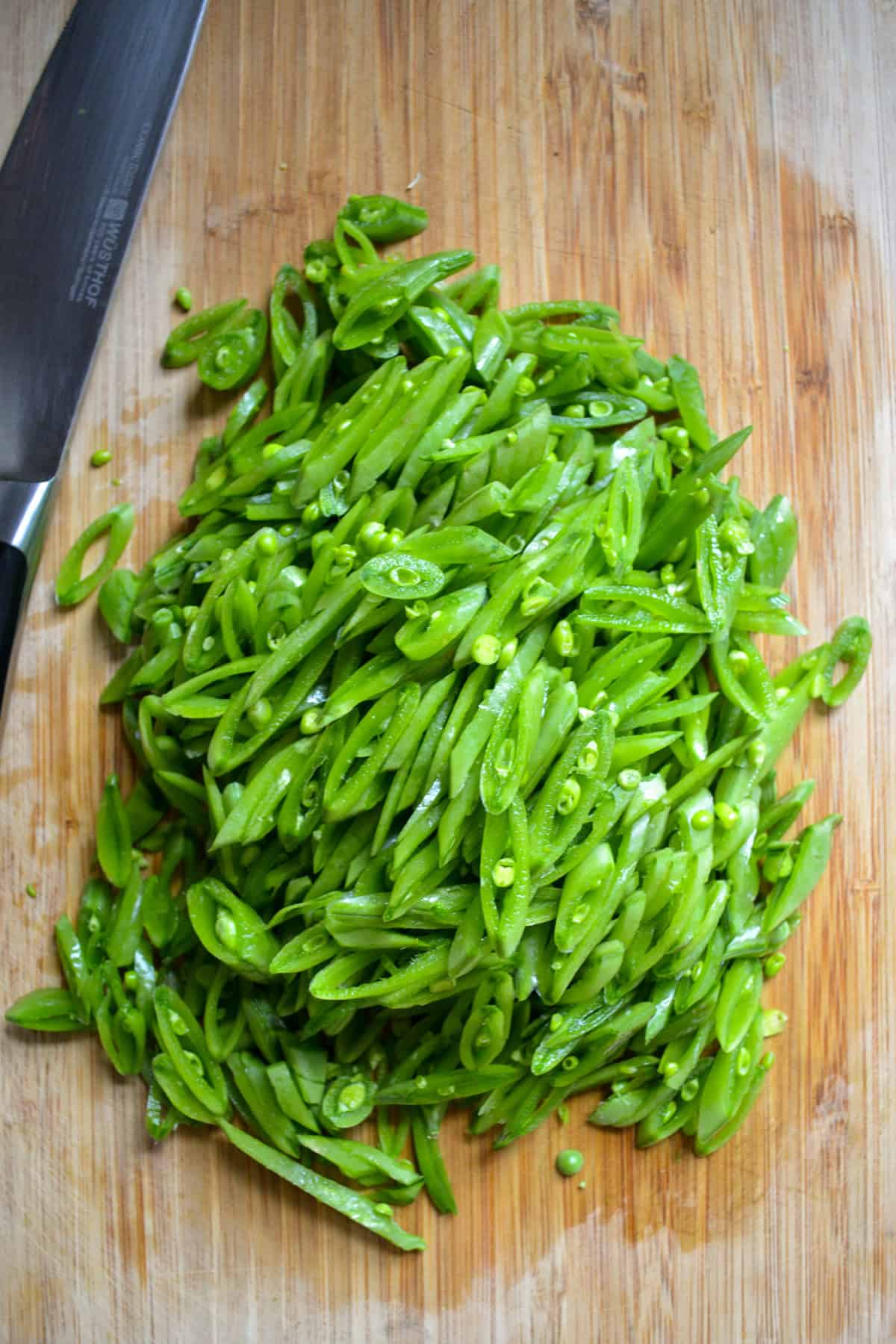 Thinly sliced snap peas on a cutting board.