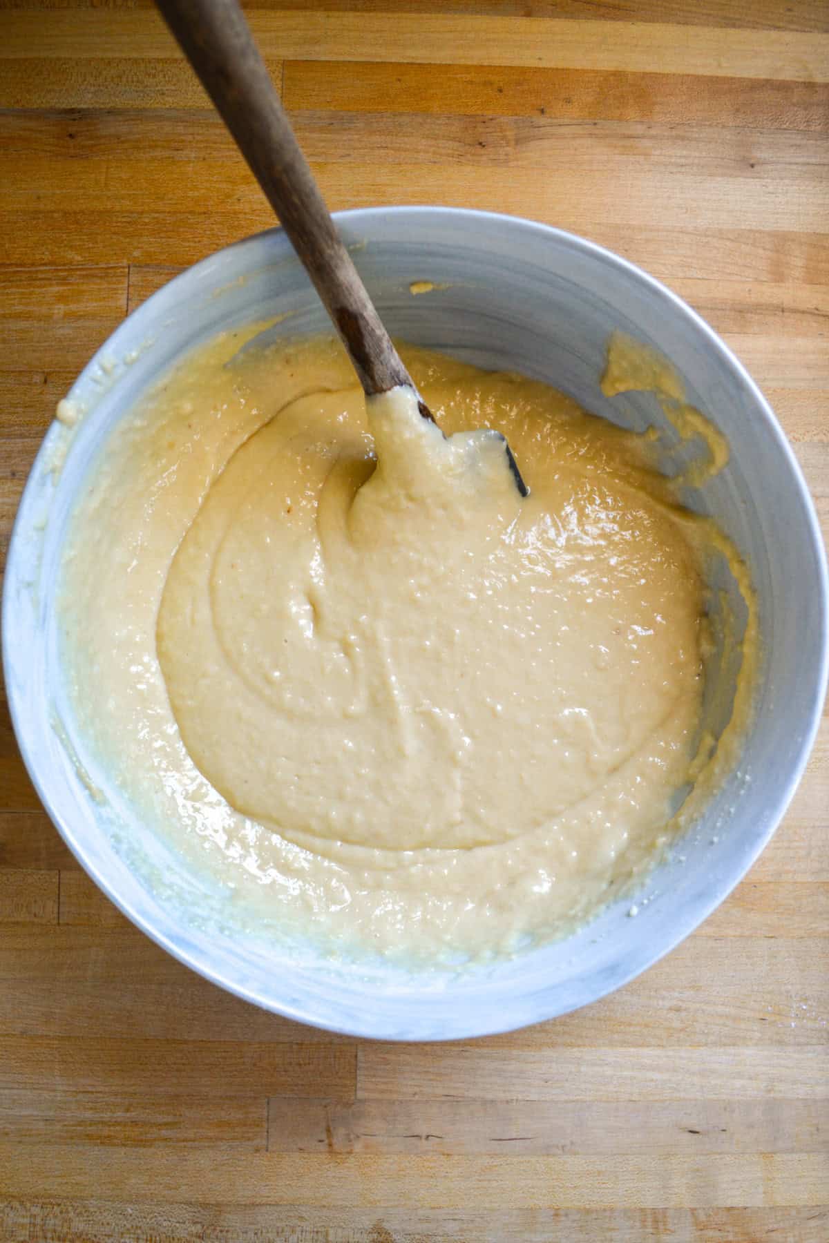 Batter in a large mixing bowl on a wooden surface.