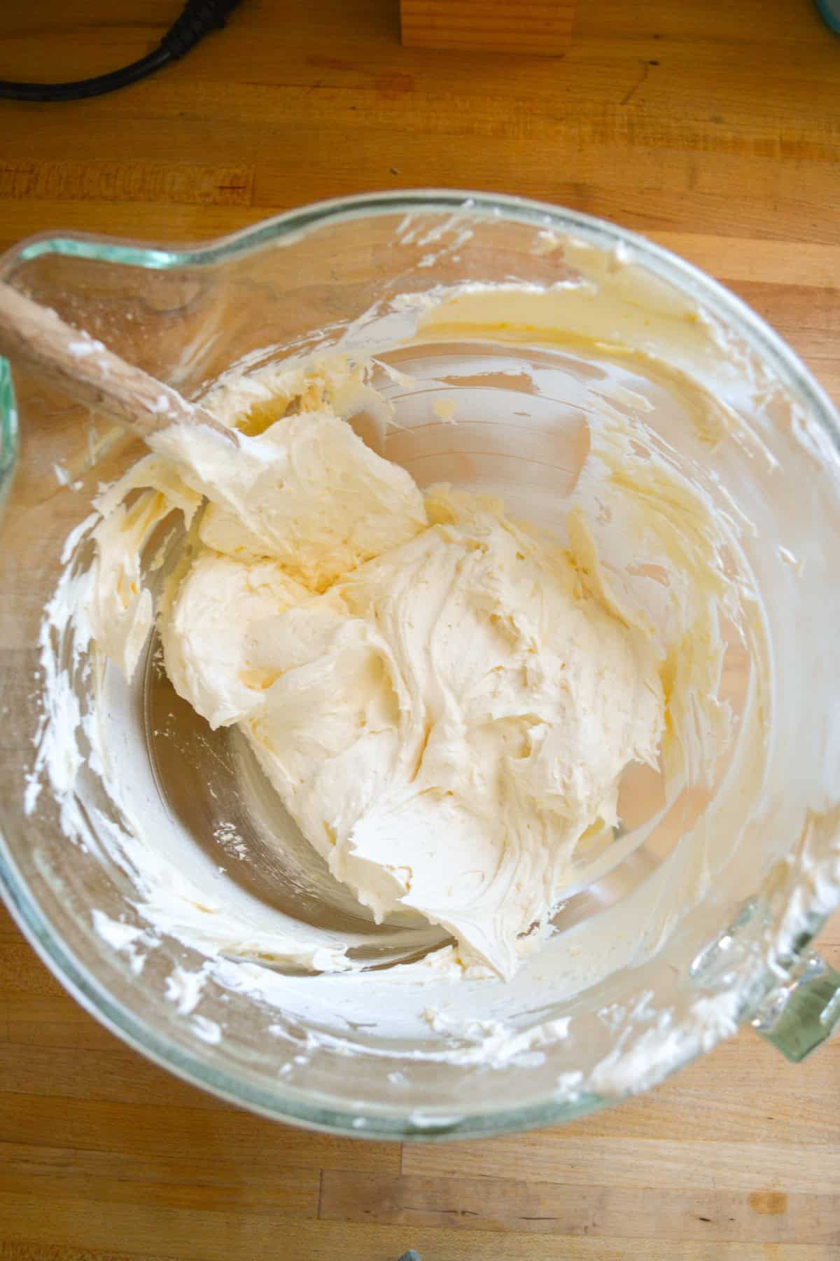 Lemon frosting in a mixing bowl with a spatula inside.