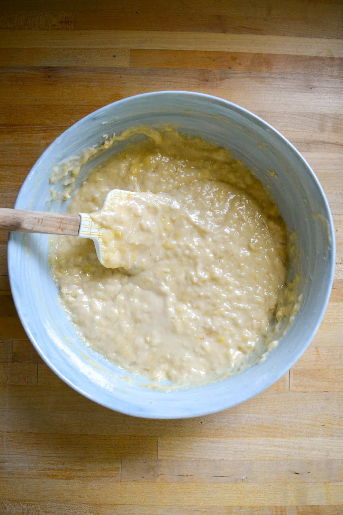 Batter in a mixing bowl on a wooden surface.