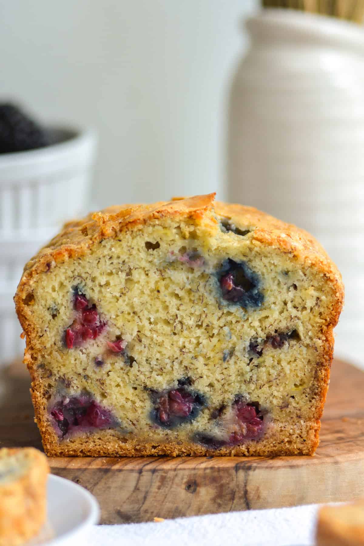 Blackberry Banana Bread loaf on a small wooden cutting board.
