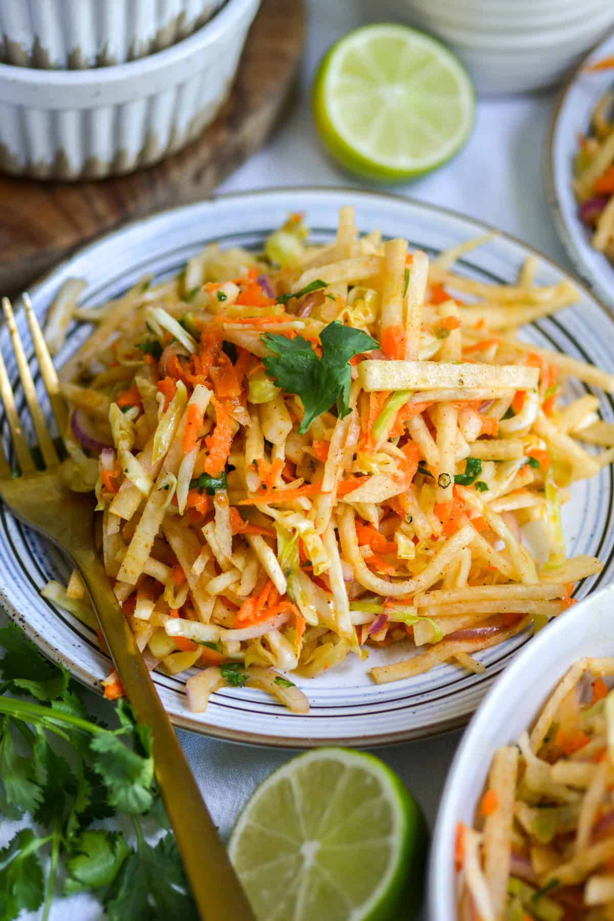 Jicama Slaw on a small plate with a gold fork.