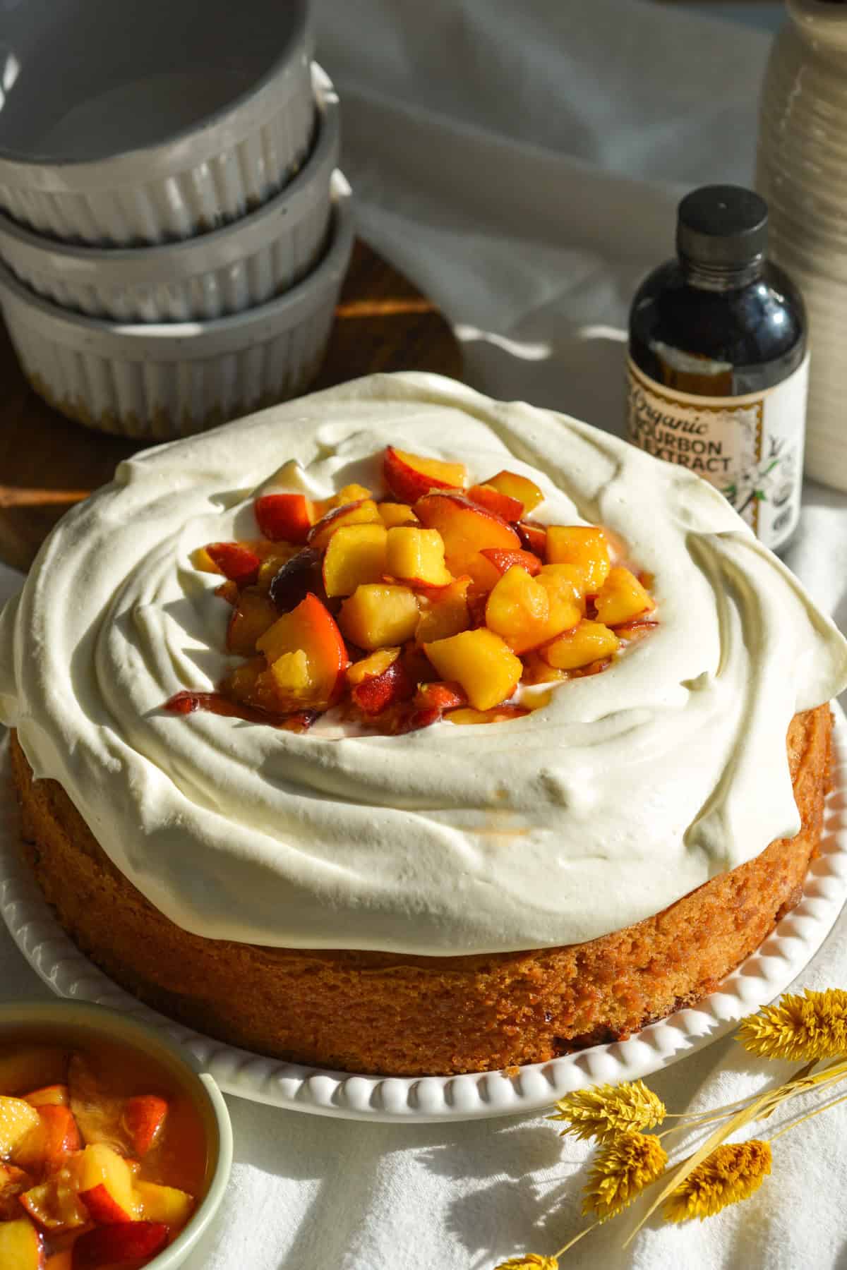 Peaches and Cream Cake on a cake plate on a linen surface.