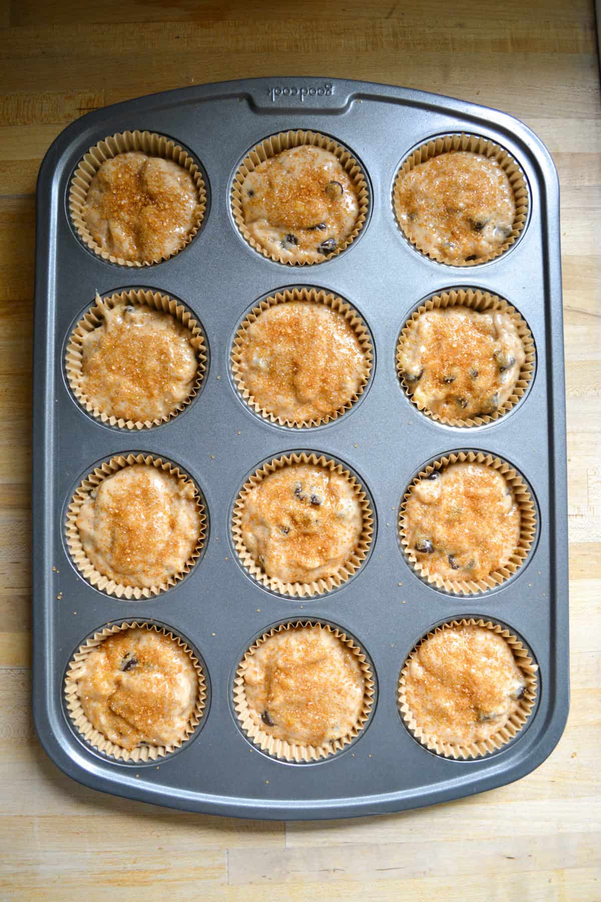 Muffin batter scooped into a lined muffin tin.