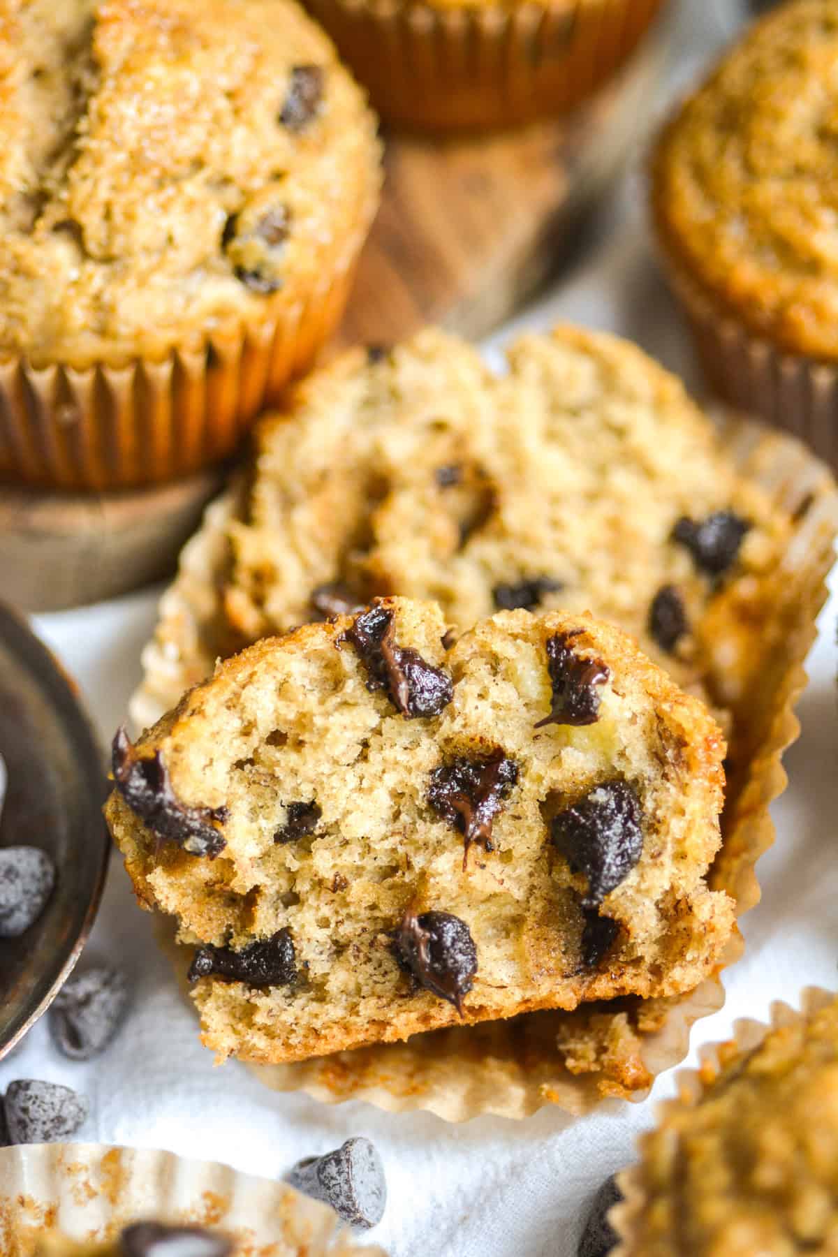A Vegan Banana Muffin with chocolate chips that is cut in half to show the fluffy interior.