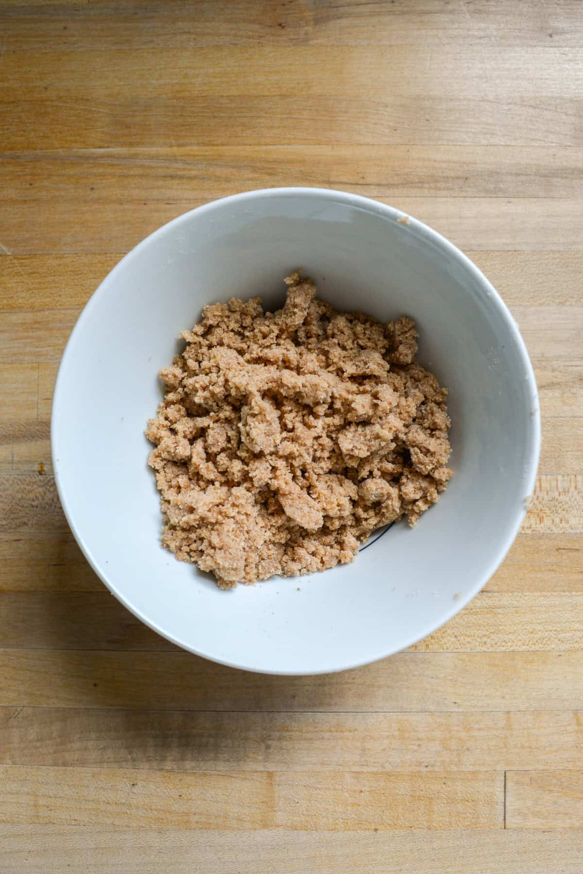 Vegan Streusel in a bowl on a wooden surface.
