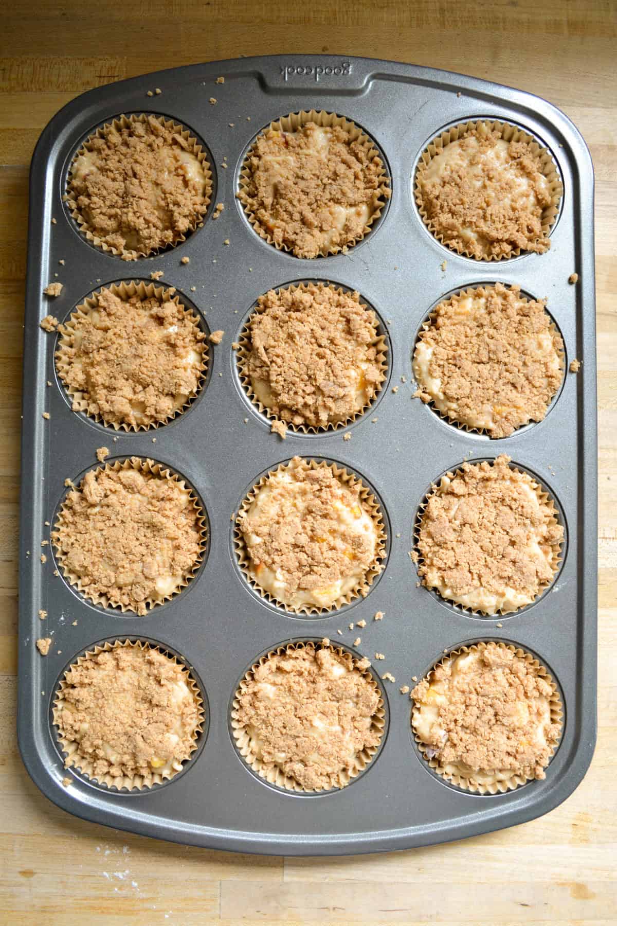 Muffin batter scooped into a muffin tin topped with streusel.