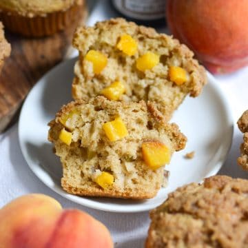 A Vegan Peach Coffee Cake Muffin cut in half on a small plate.