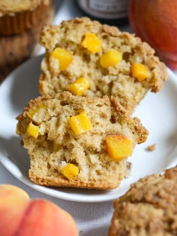 A Vegan Peach Coffee Cake Muffin cut in half on a small plate.