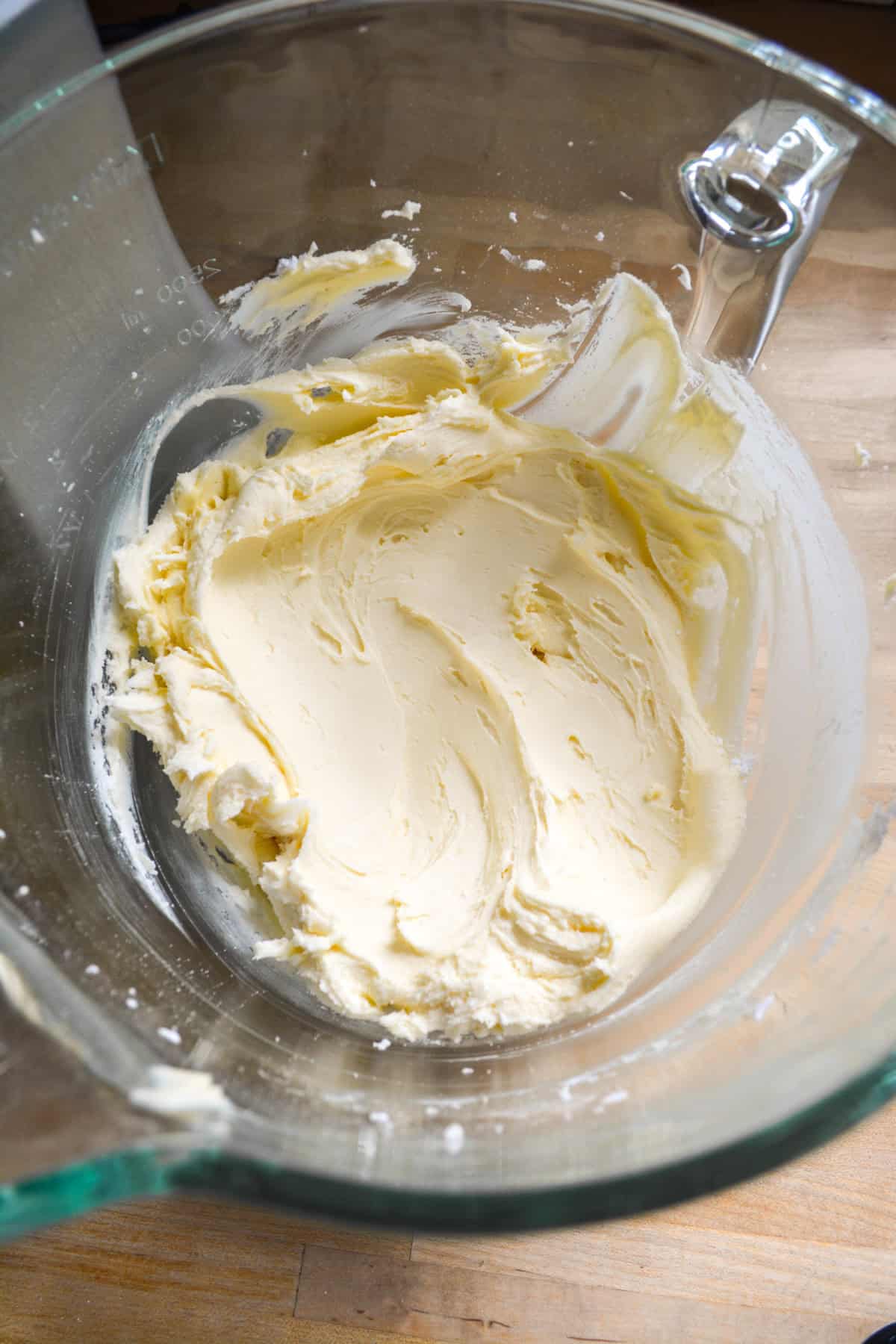 Powdered sugar added to the vegan butter in a glass mixing bowl.