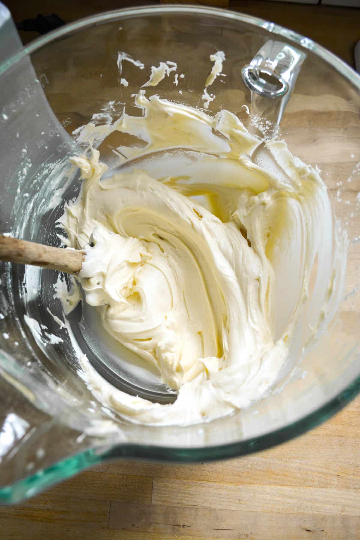 Vegan Vanilla Frosting in a glass bowl with a rubber spatula inside.
