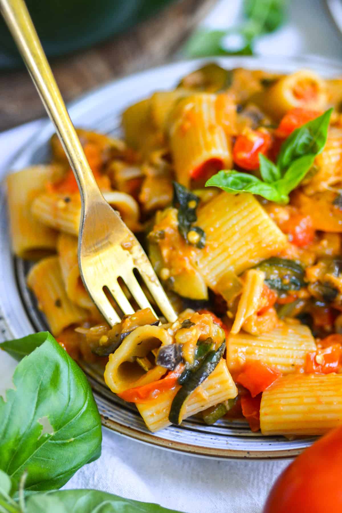 A fork with a bite of Creamy Roasted Vegetable Pasta on in on a plate of pasta.