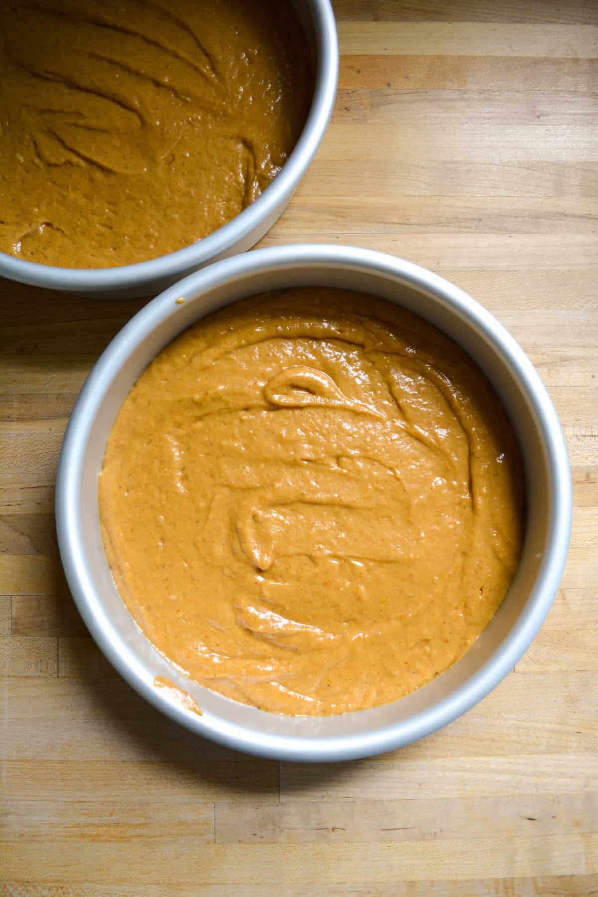 Cake batter divided into two round cake pans.
