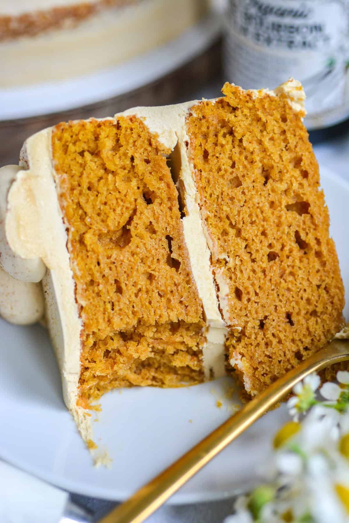 A slice of Vegan Pumpkin Cake on a white plate with a bite taken out of it.