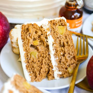 A slice of Vegan Apple cake on a plate with a gold fork.