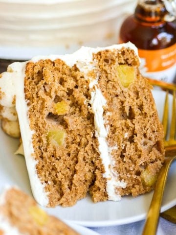 A slice of Vegan Apple cake on a plate with a gold fork.