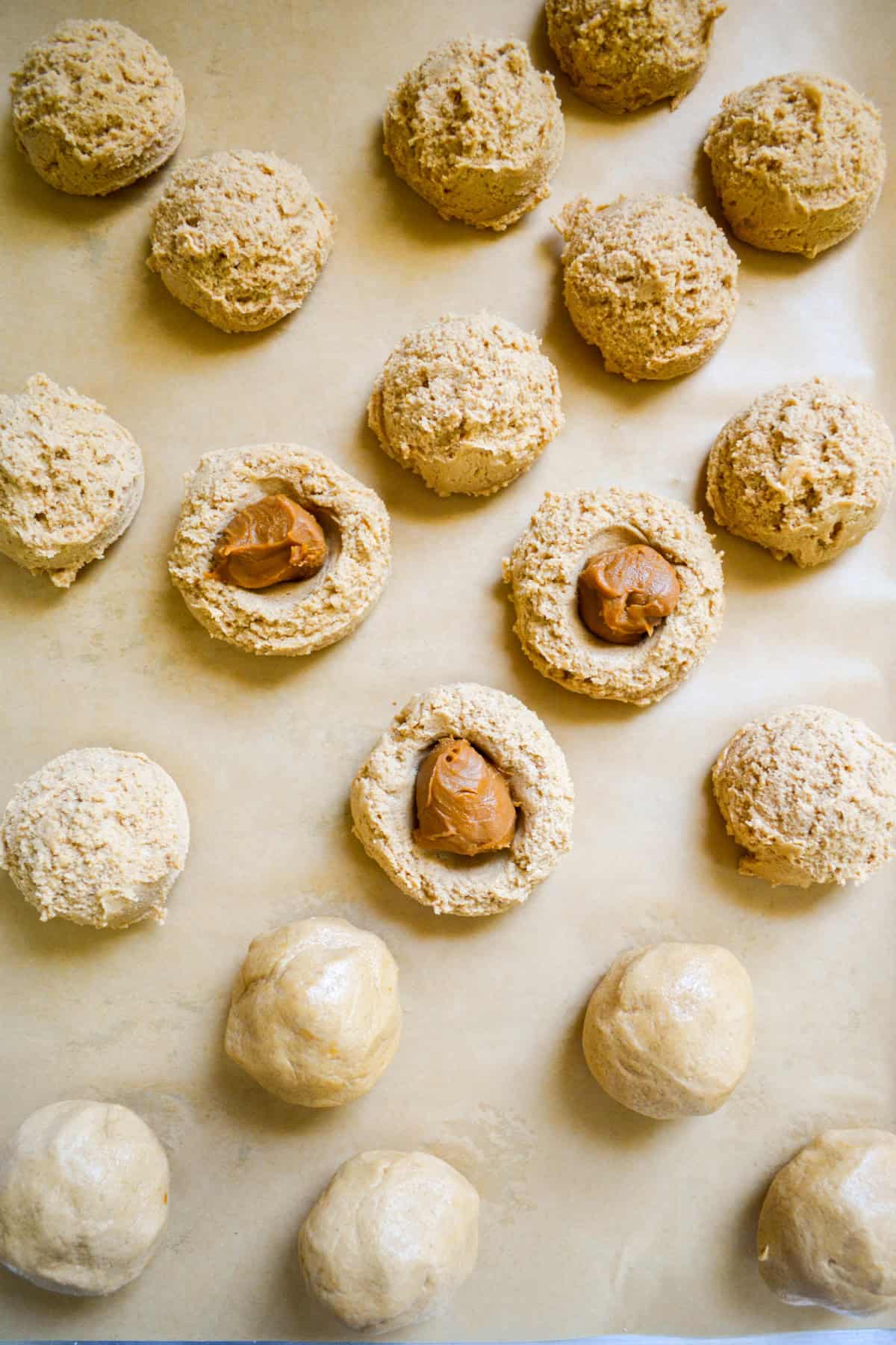 Scooped cookie dough begin filled with balls of Biscoff.