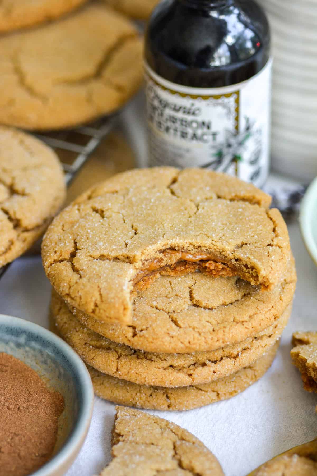 A Vegan Biscoff Stuffed Cookie with a bite taken out of it on a stack of other cookies.