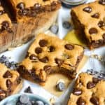 A Gluten-Free Peanut Butter Blondie with a bite taken out of it on a square of parchment.