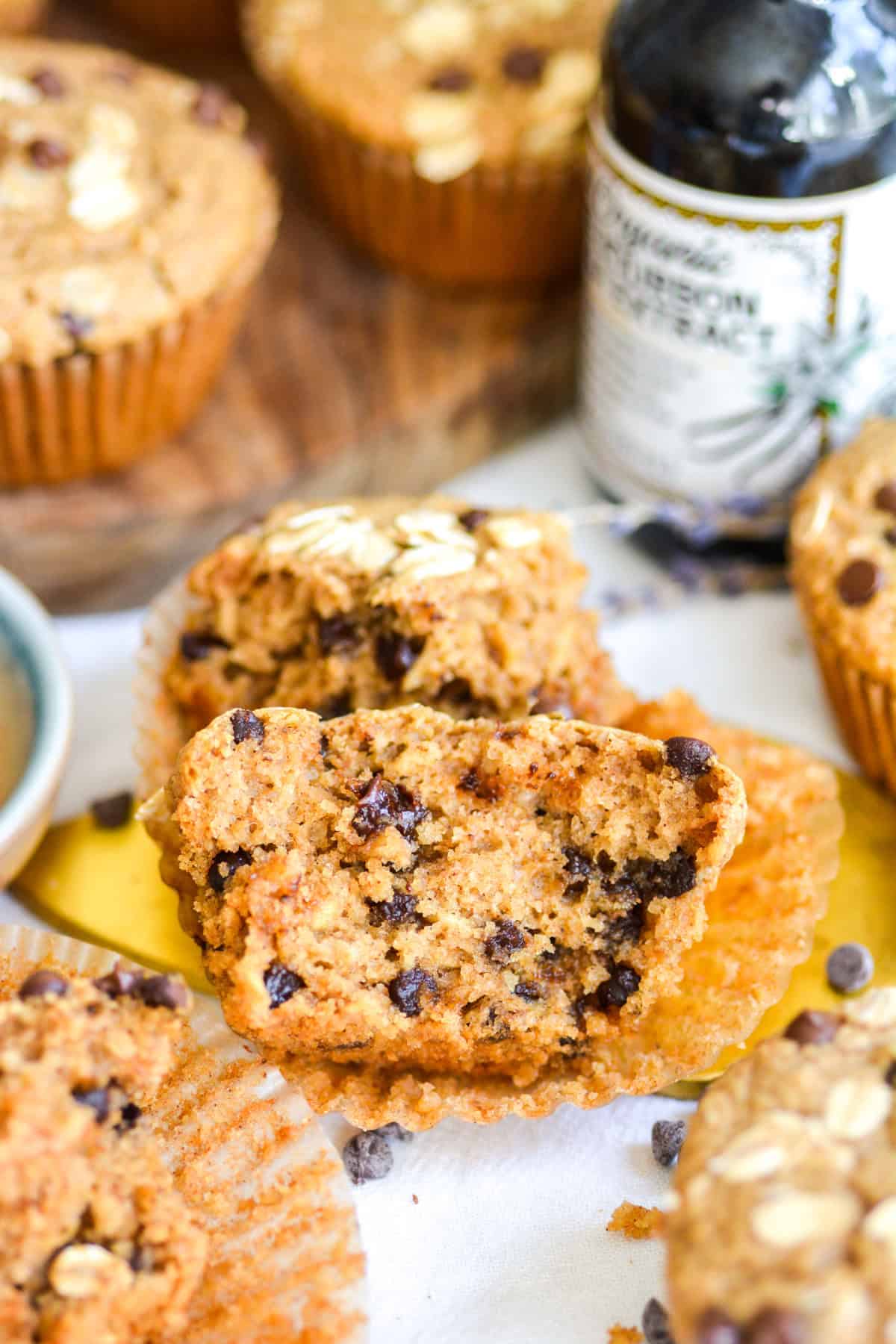 An Oat Flour Chocolate Chip Muffin brown in half on a paper muffin liner.